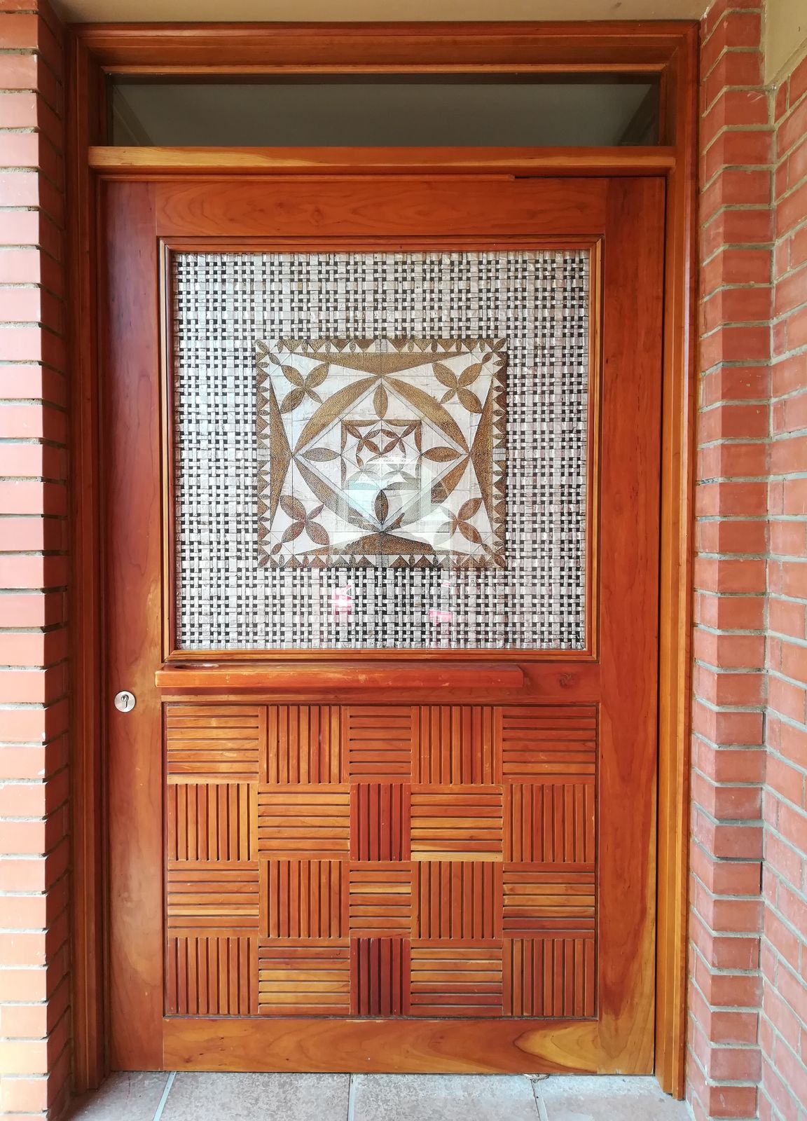 A custom timber front door with a woven slatted panel