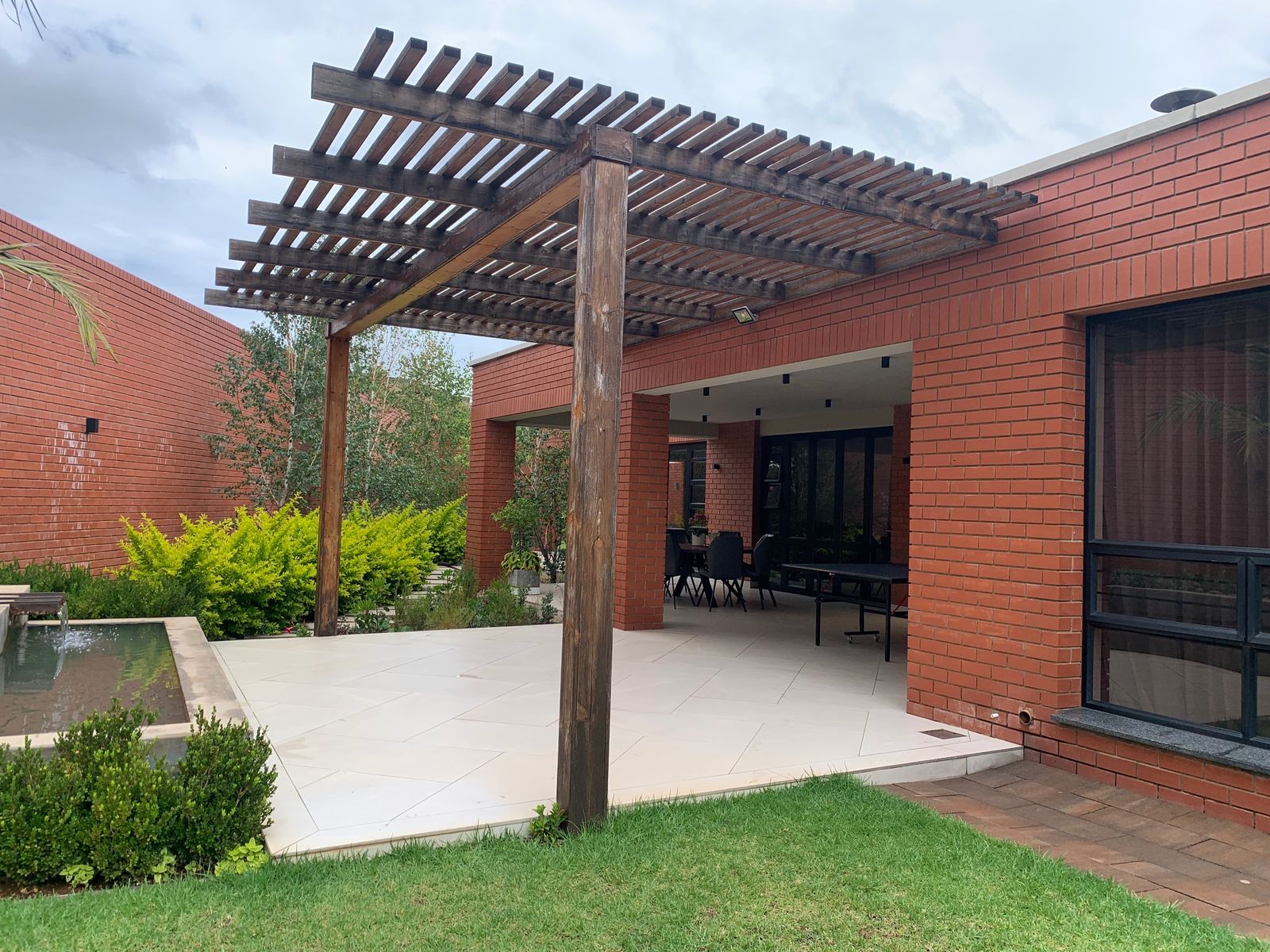 A timber pergola over a patio beside a water feature