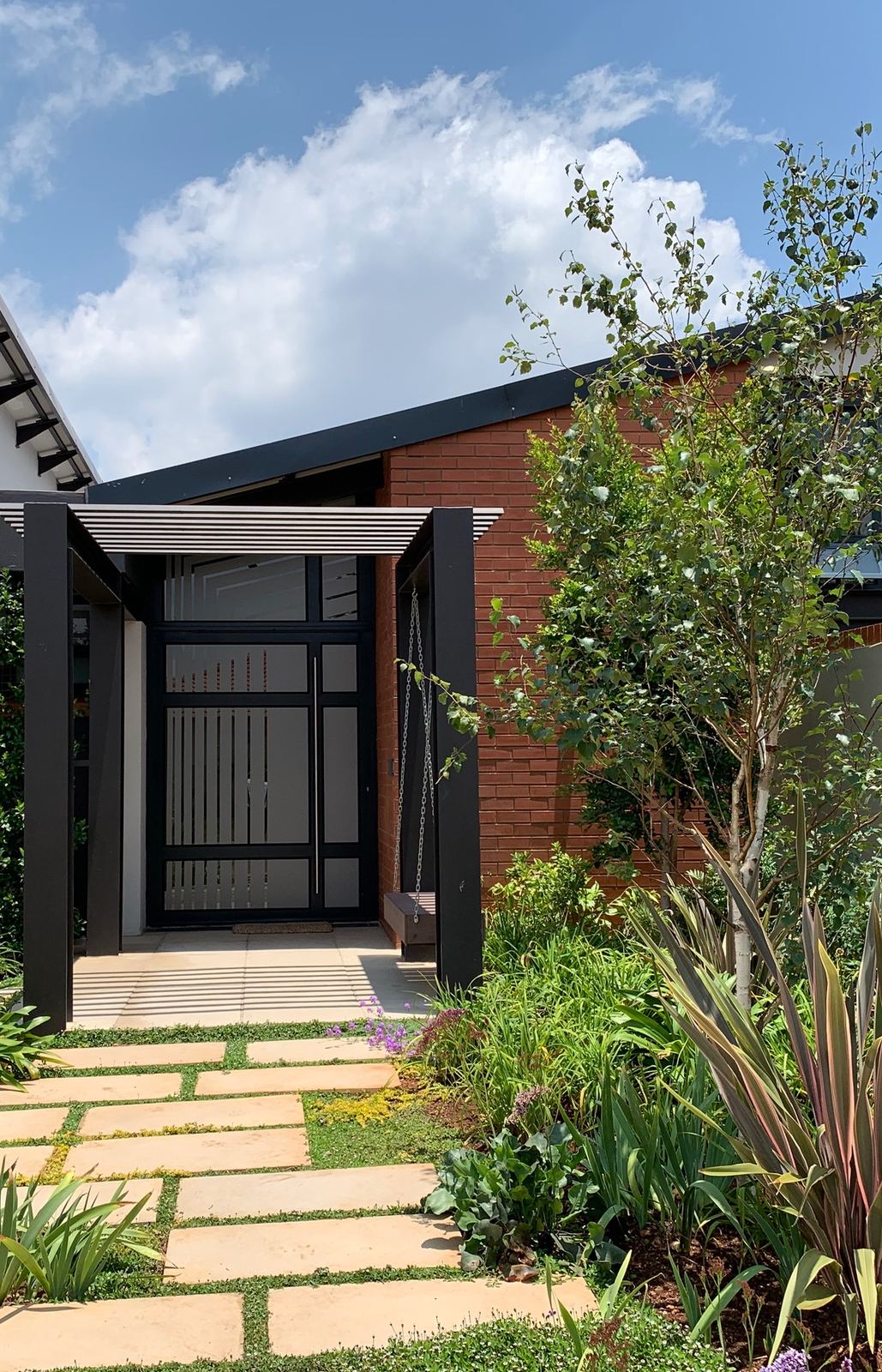 A steel portico and stepping-stone path to the front door