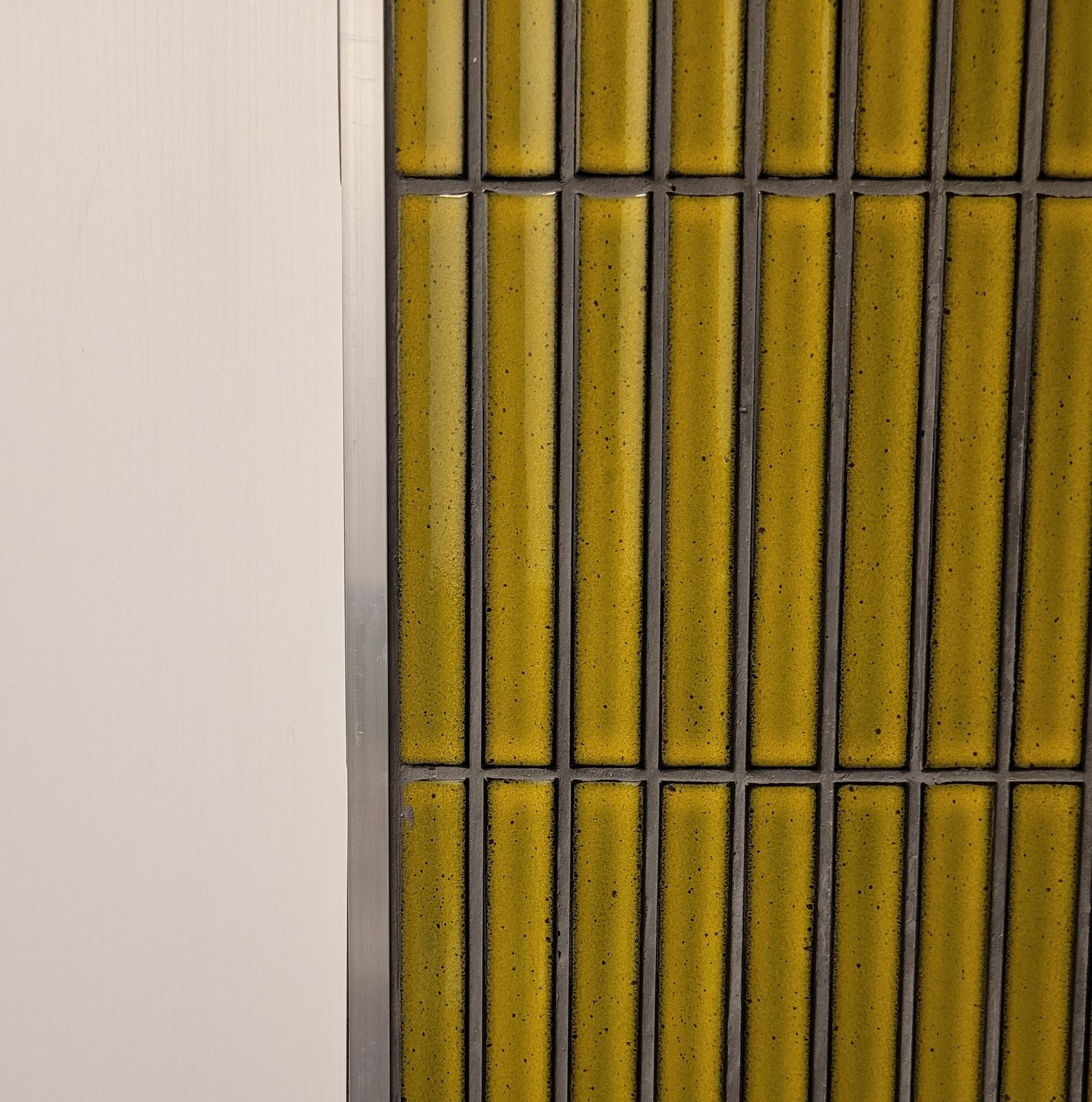 Glazed tiles finished cleanly against a slim metal trim