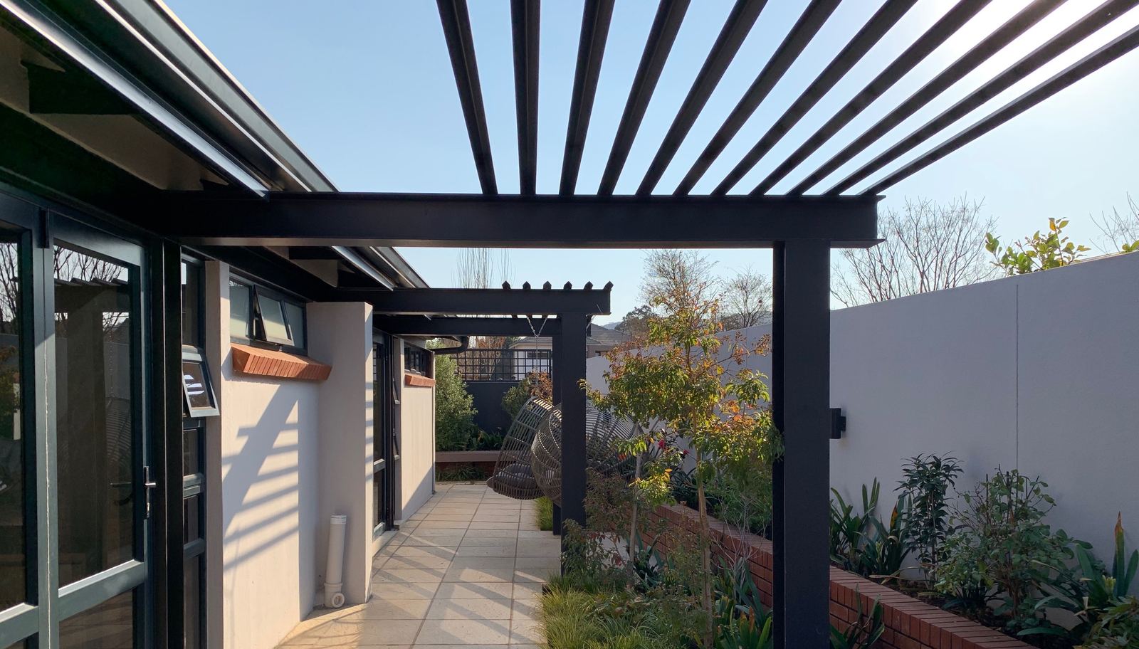 A shaded steel pergola walkway along the bedrooms